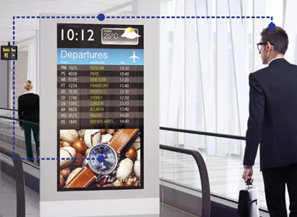 A traveller beside an airport departures screen with a face-detection box around the viewer
